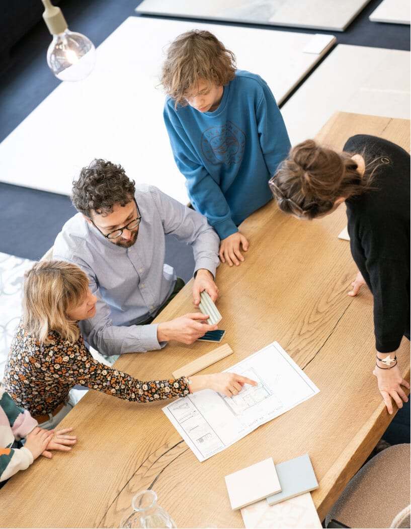 Beratung am Tisch, ein Mitarbeiter erklärt einer Familie die Planung